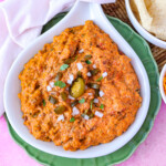 warm chili cheese dip ready to serve with cilantro, jalapeno and onions on top