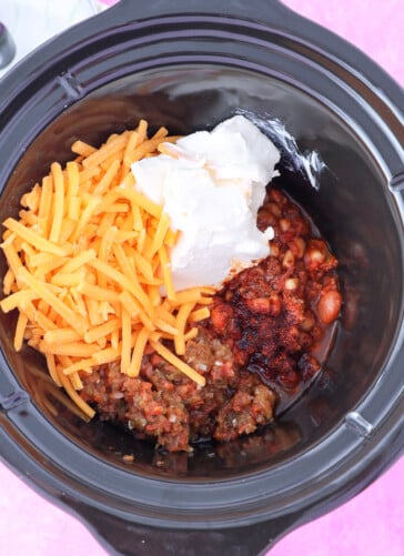 5 ingredients in a crock pot for chili cheese dip ready to stir