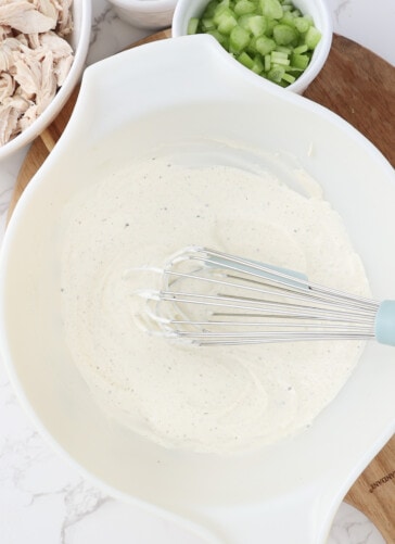 Creamy chicken salad dressing mixed in a bowl with a whisk