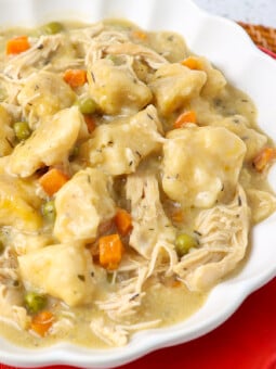 Cooked chicken dumplings with gravy on top of shredded chicken and carrots