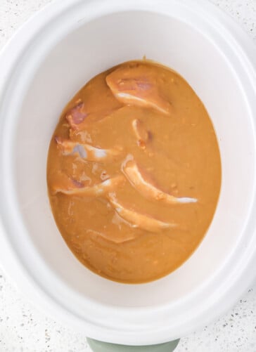 Sauce that has been poured over the pork chops in a crock pot ready to cook