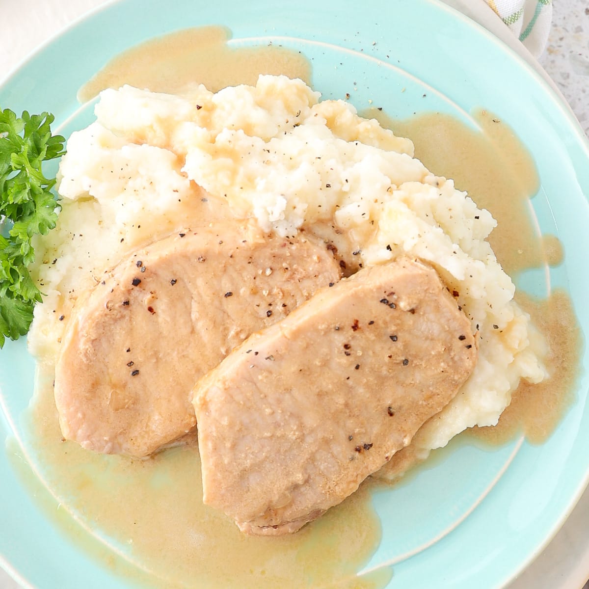 Five ingredient pork chops ready for dinner drizzled with gravy on mashed potatoes