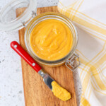 Yellow mustard that has been made from scratch curing in a jar and being tasted on a knife