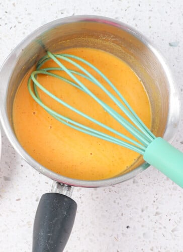 Homemade yellow mustard being cooked in a pan and stirred with a whisk