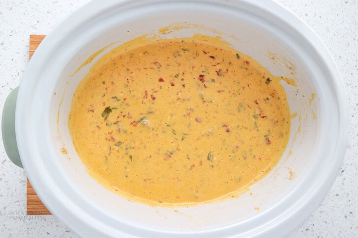 A crock pot full of sausage Rotel dip that has been cooked and stirred together