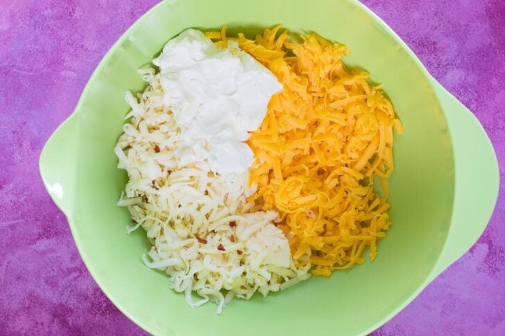 cheddar cheeses and cream cheese being blended in a bowl.