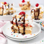 banana split cake with chocolate topping, peanus, and a cherry