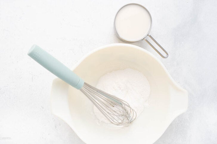 pudding mix in a bowl with milk and whisk
