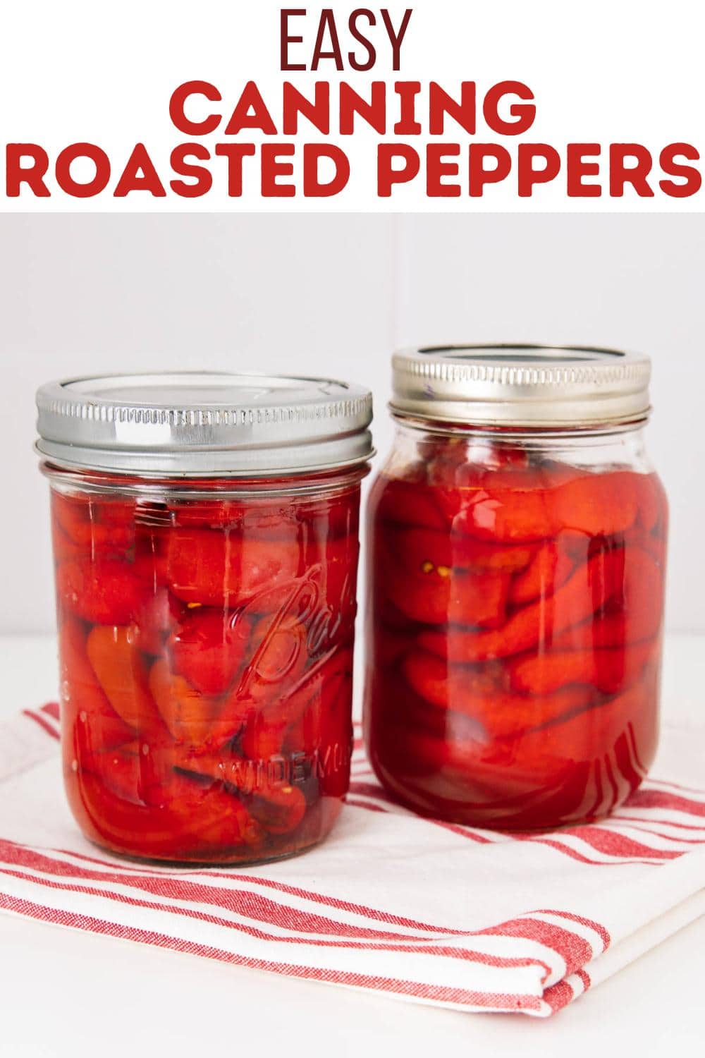 Two glass jars filled with bright red roasted peppers, sealed with metal lids, sit on a white and red striped cloth. Text above reads “Easy Canning Roasted Peppers” in large, bold red letters.