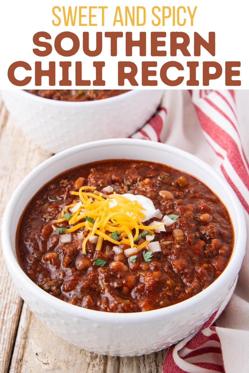 A white bowl filled with chili, topped with shredded cheese, sour cream, and herbs, sits on a wooden surface next to a red-striped napkin. Text above reads, "Sweet and Spicy Southern Chili Recipe.