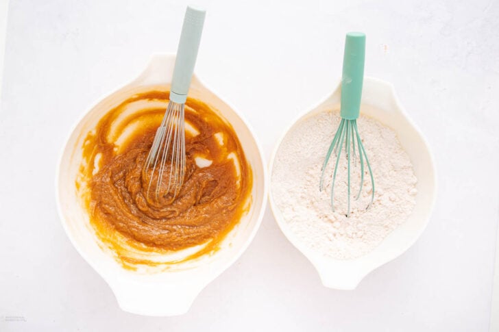 Two mixing bowls with turquoise whisks: one contains a brown wet mixture, and the other holds dry flour. Both bowls are placed on a white surface, viewed from above.