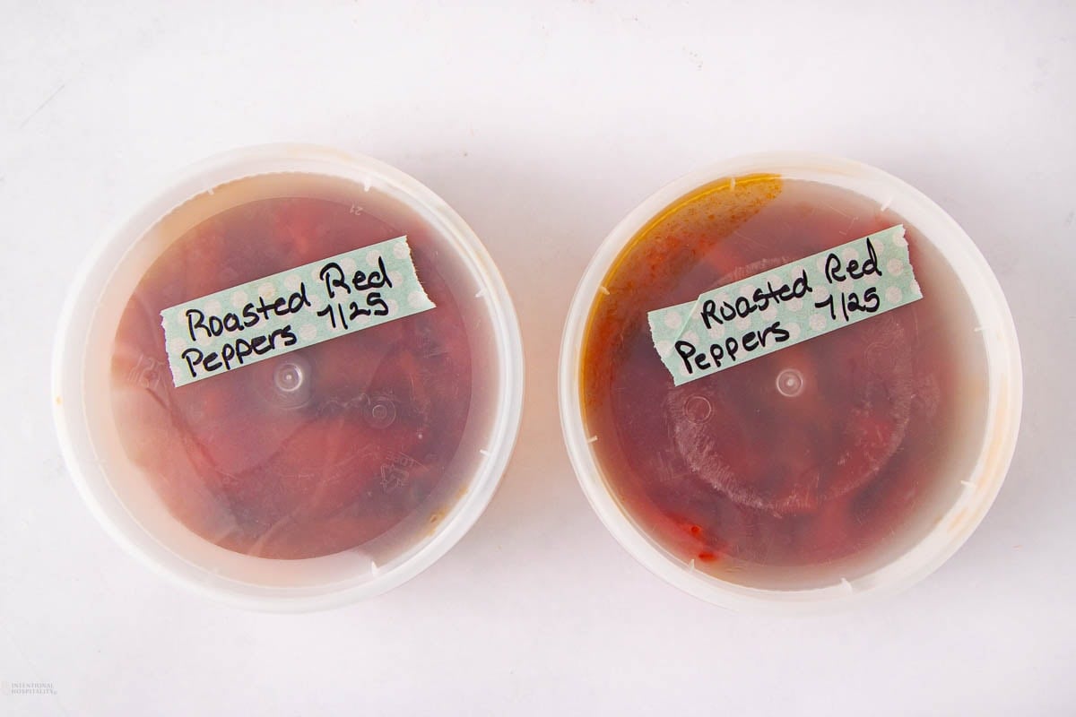 Two plastic containers filled with roasted red peppers, each labeled "Roasted Red Peppers 7/25" with handwritten text on green tape, placed on a white surface.