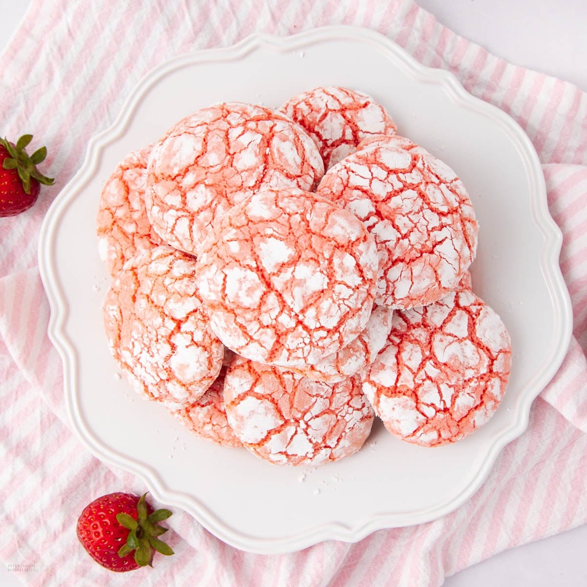 A plate of strawberry crinkle cookies dusted with powdered sugar.