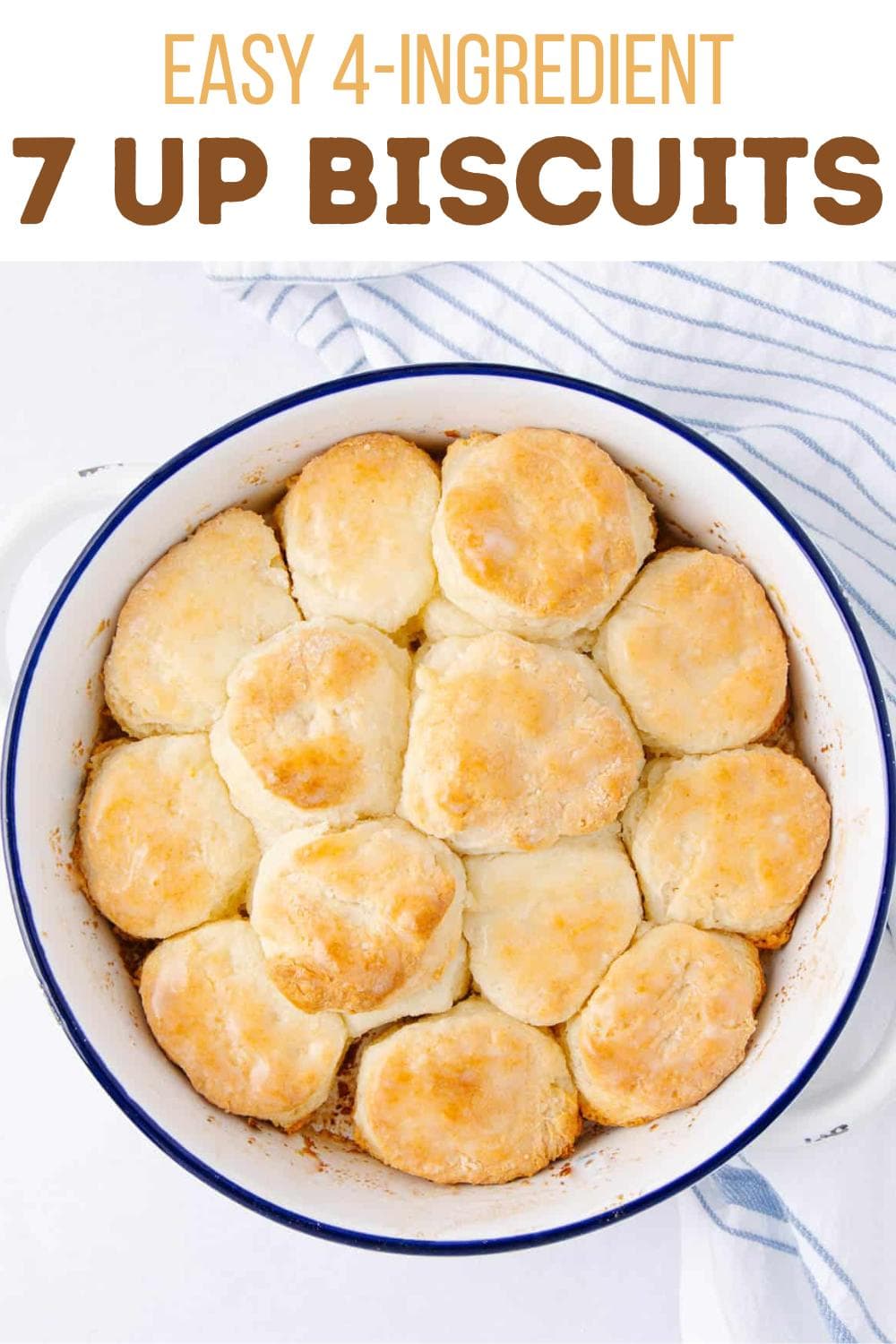 A round baking dish filled with golden, fluffy biscuits. The dish sits on a striped white and blue towel. Text above reads "Easy 4-Ingredient 7 Up Biscuits.