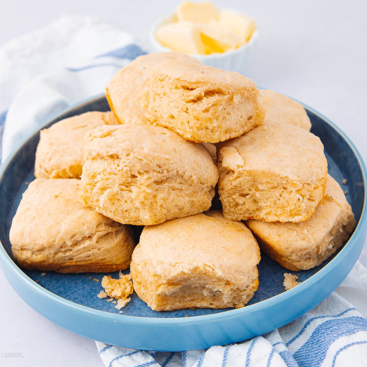 A blue plate filled with golden brown, fluffy biscuits stacked on top of each other.