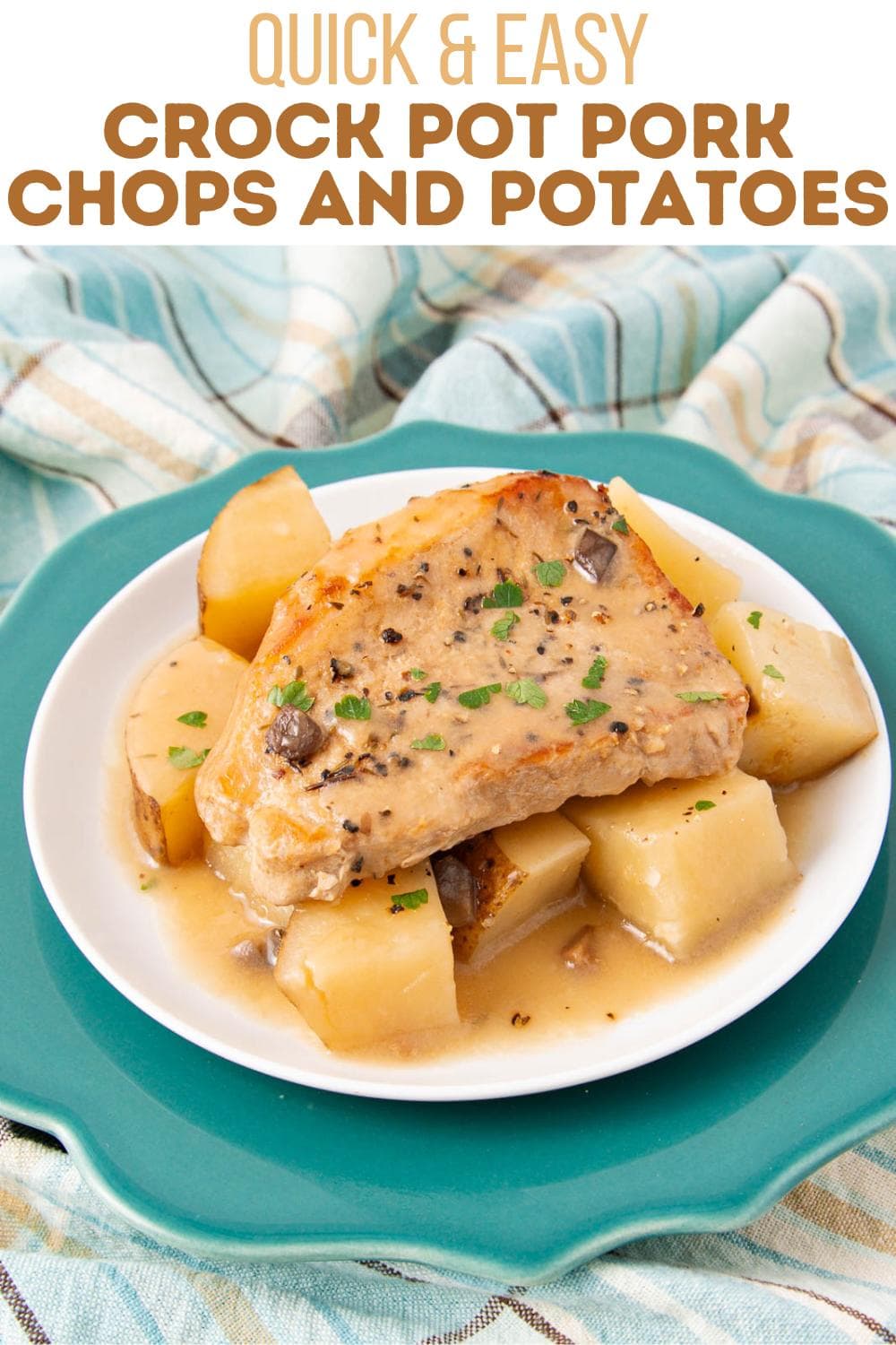 A plate with a pork chop and chunky potatoes in gravy, garnished with herbs. The plate is on a teal charger, over a plaid cloth. Text above reads: "Quick & Easy Crock Pot Pork Chops and Potatoes.