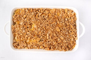 A white rectangular baking dish filled with a golden-brown, crumbly casserole topping, viewed from above on a white background.