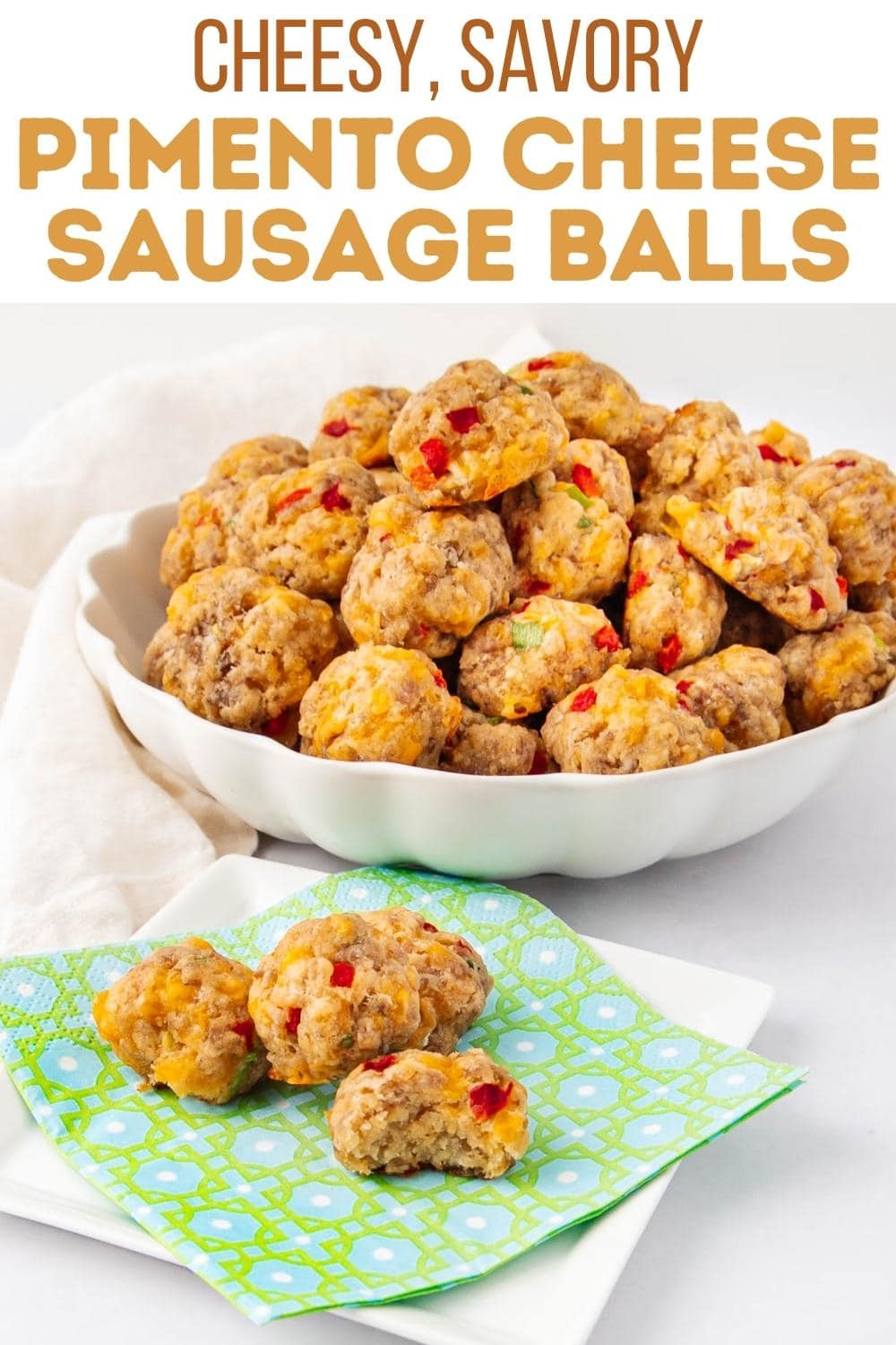 A white bowl filled with pimento cheese sausage balls sits on a white surface. Three sausage balls rest on a green-patterned napkin beside the bowl. Text above reads "Cheesy, Savory Pimento Cheese Sausage Balls.