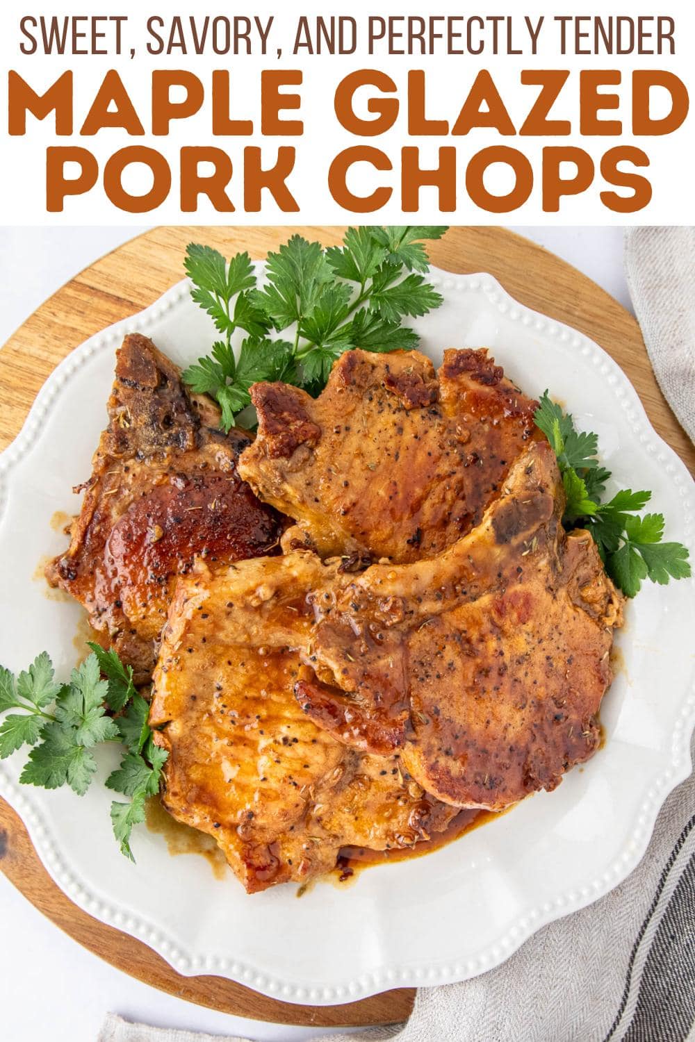 A white plate with three glazed pork chops garnished with fresh parsley sits on a wooden board. Text above reads, "Sweet, Savory, and Perfectly Tender Maple Glazed Pork Chops.