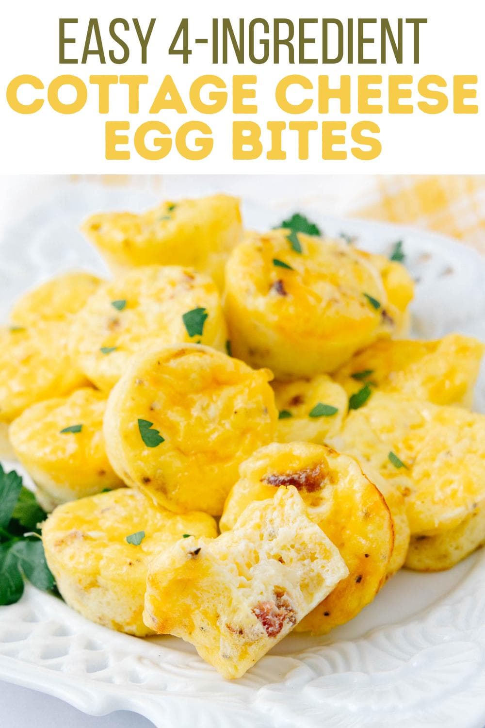 A plate of golden cottage cheese egg bites garnished with parsley. One egg bite in the front has a bite taken out, showing a fluffy, cheesy interior. Text at the top reads, "Easy 4-ingredient Cottage Cheese Egg Bites.