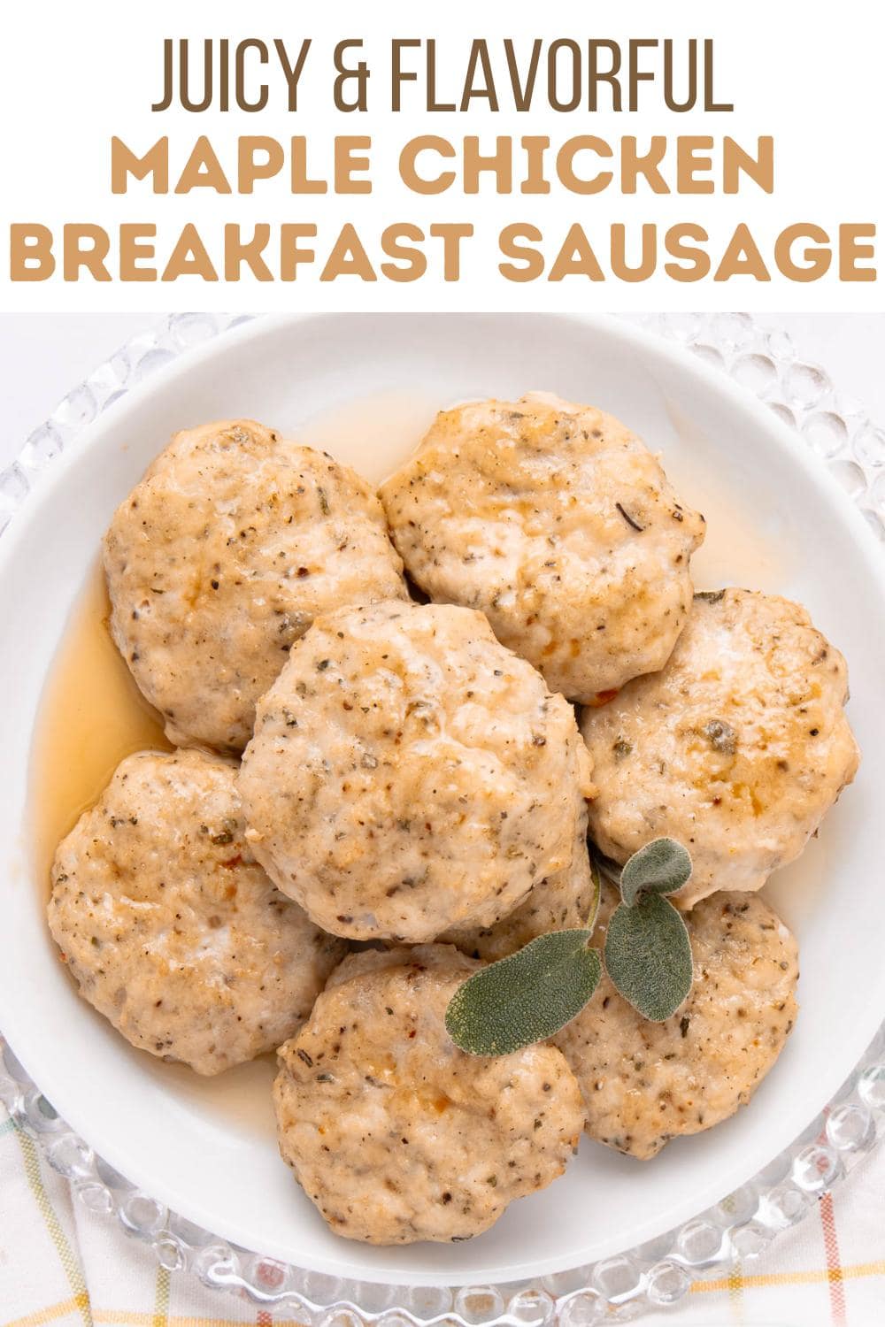 A white plate with six round maple chicken breakfast sausages garnished with fresh sage leaves, placed on a clear glass charger. Text above reads, "Juicy & Flavorful Maple Chicken Breakfast Sausage.