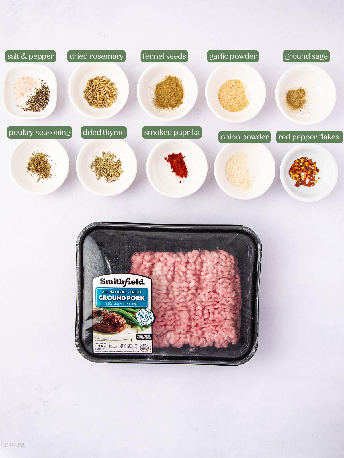 A package of ground pork sits below ten small bowls, each containing a different spice or seasoning including rosemary, fennel seeds, garlic powder, sage, and more, all labeled with green text.