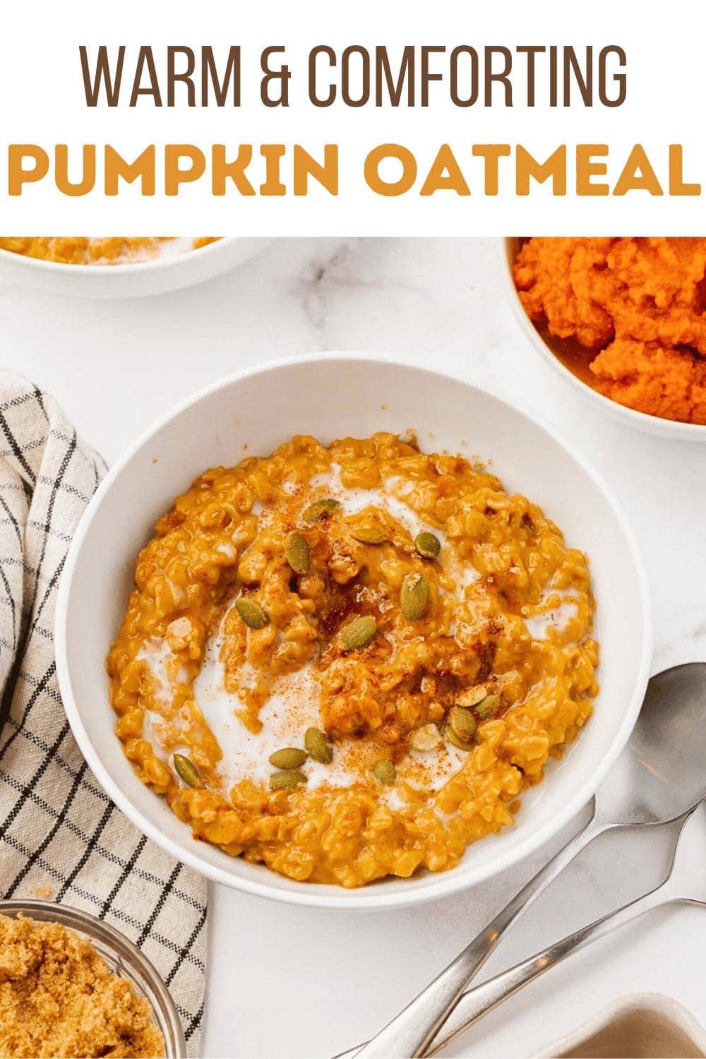A bowl of pumpkin oatmeal topped with pumpkin seeds, cinnamon, and a swirl of milk, surrounded by a spoon, a bowl of mashed pumpkin, a dish of brown sugar, and a checkered napkin. Text above reads "Warm & Comforting Pumpkin Oatmeal.