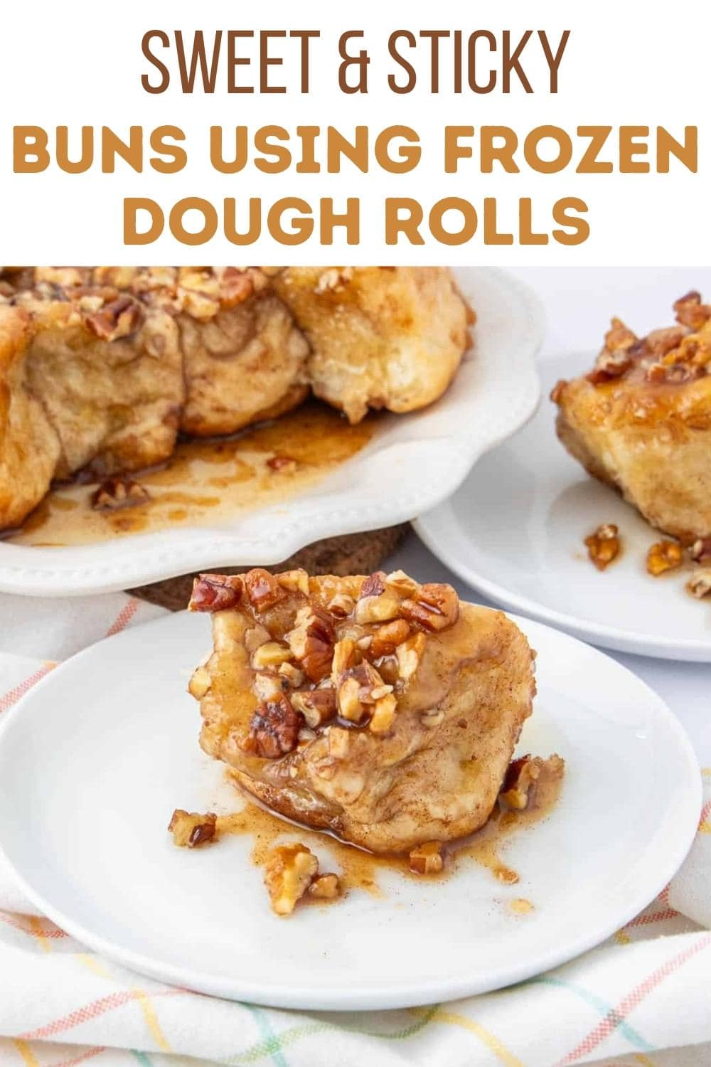 A plate with a sweet, sticky bun topped with chopped nuts and syrup sits in the foreground, with more buns served on plates in the background. Text above reads, "Sweet & Sticky Buns Using Frozen Dough Rolls.