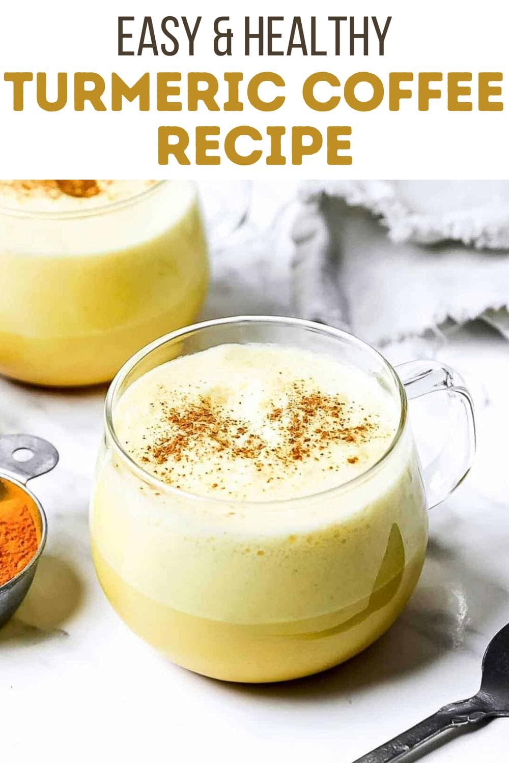 A clear glass mug filled with frothy turmeric coffee, sprinkled with cinnamon, sits on a white surface next to a small bowl of ground turmeric. Text at the top reads, "Easy & Healthy Turmeric Coffee Recipe.
