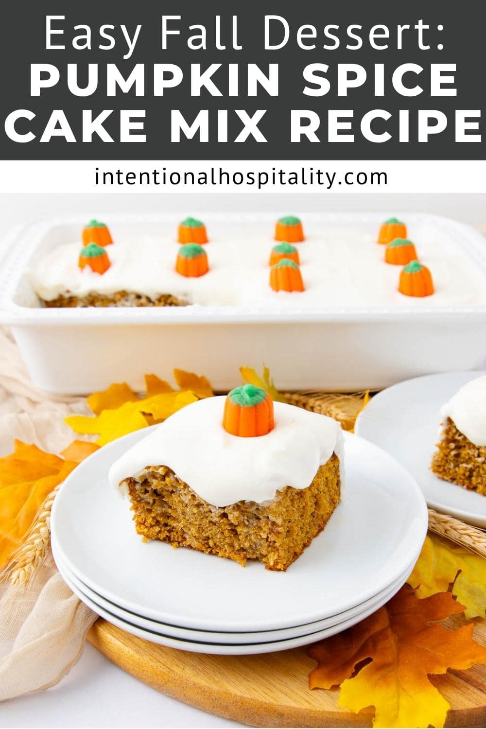 A slice of pumpkin spice cake with white frosting and a candy pumpkin on top is served on a plate. In the background, a pan of the cake and fall leaves are visible. Text above reads, "Easy Fall Dessert: Pumpkin Spice Cake Mix Recipe.