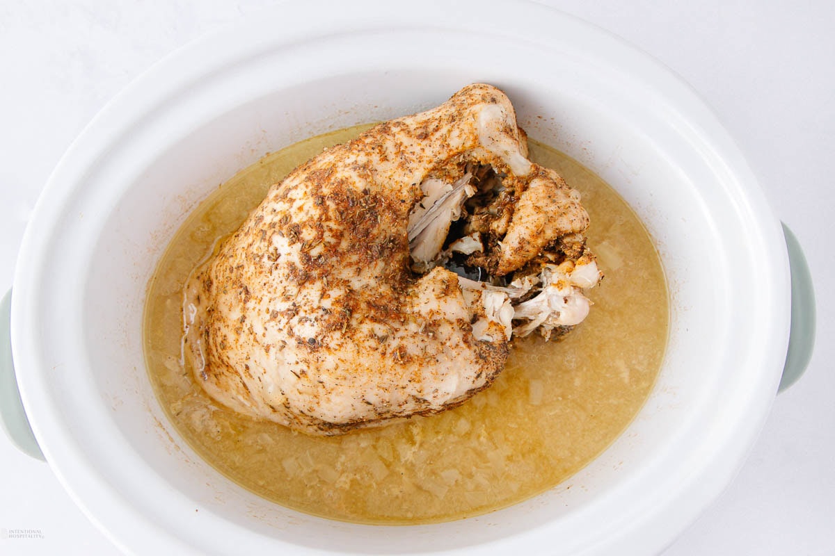 A piece of chicken in a bowl of broth.