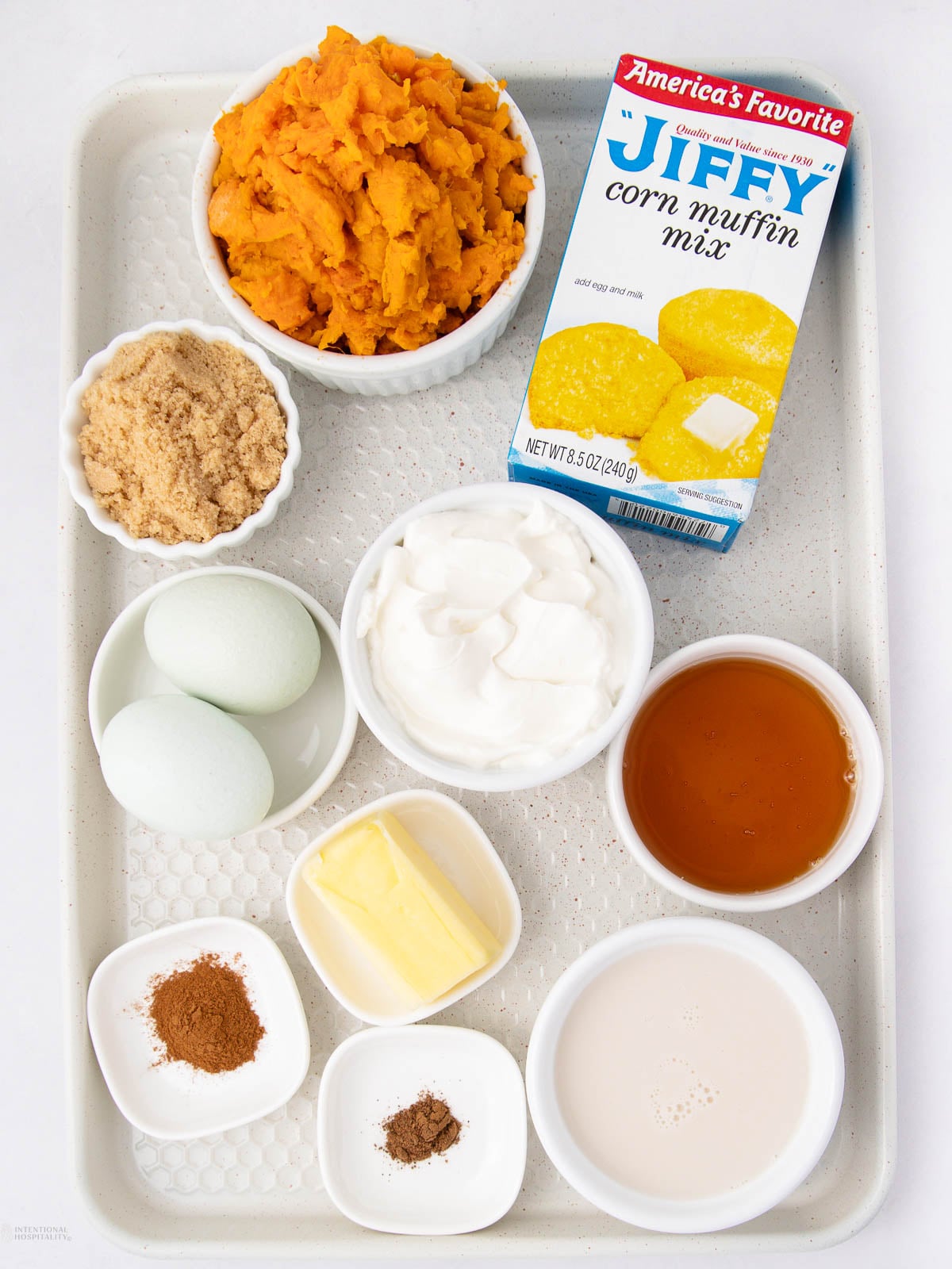 A tray with bowls of mashed sweet potatoes, brown sugar, eggs, yogurt, butter, spices, milk, honey, and a box of Jiffy corn muffin mix.