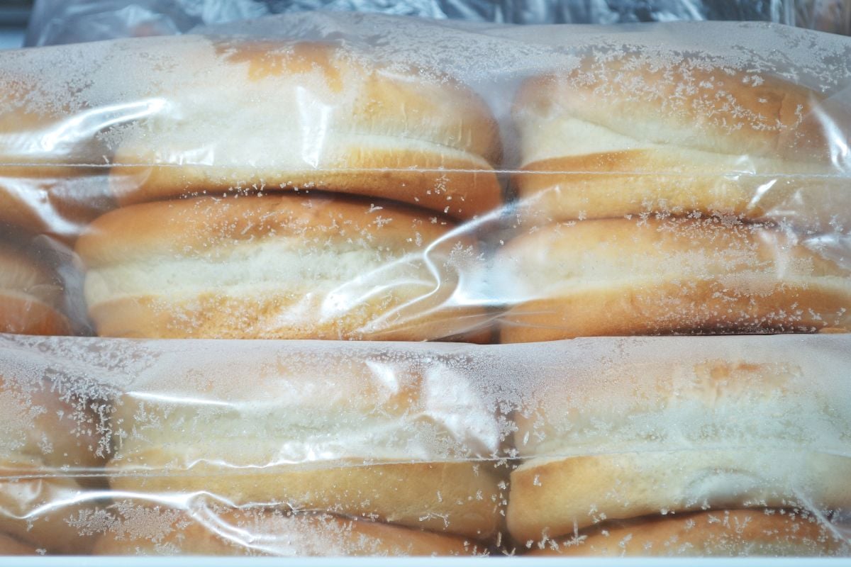 A close-up view of packaged hamburger buns in a plastic bag, showing condensation droplets on the inside of the packaging.