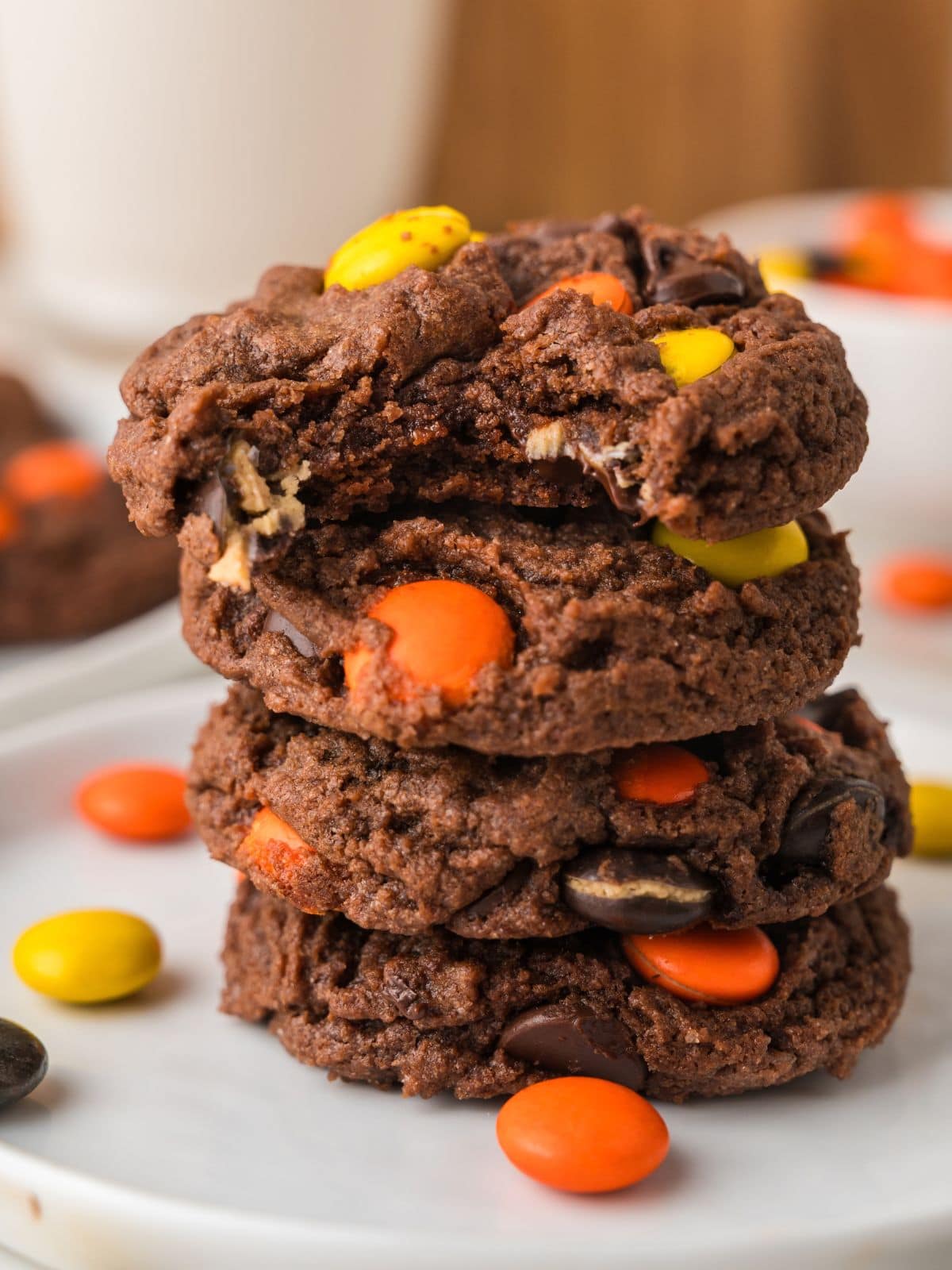 A stack of three chocolate cookies with colorful candy pieces on a white plate.