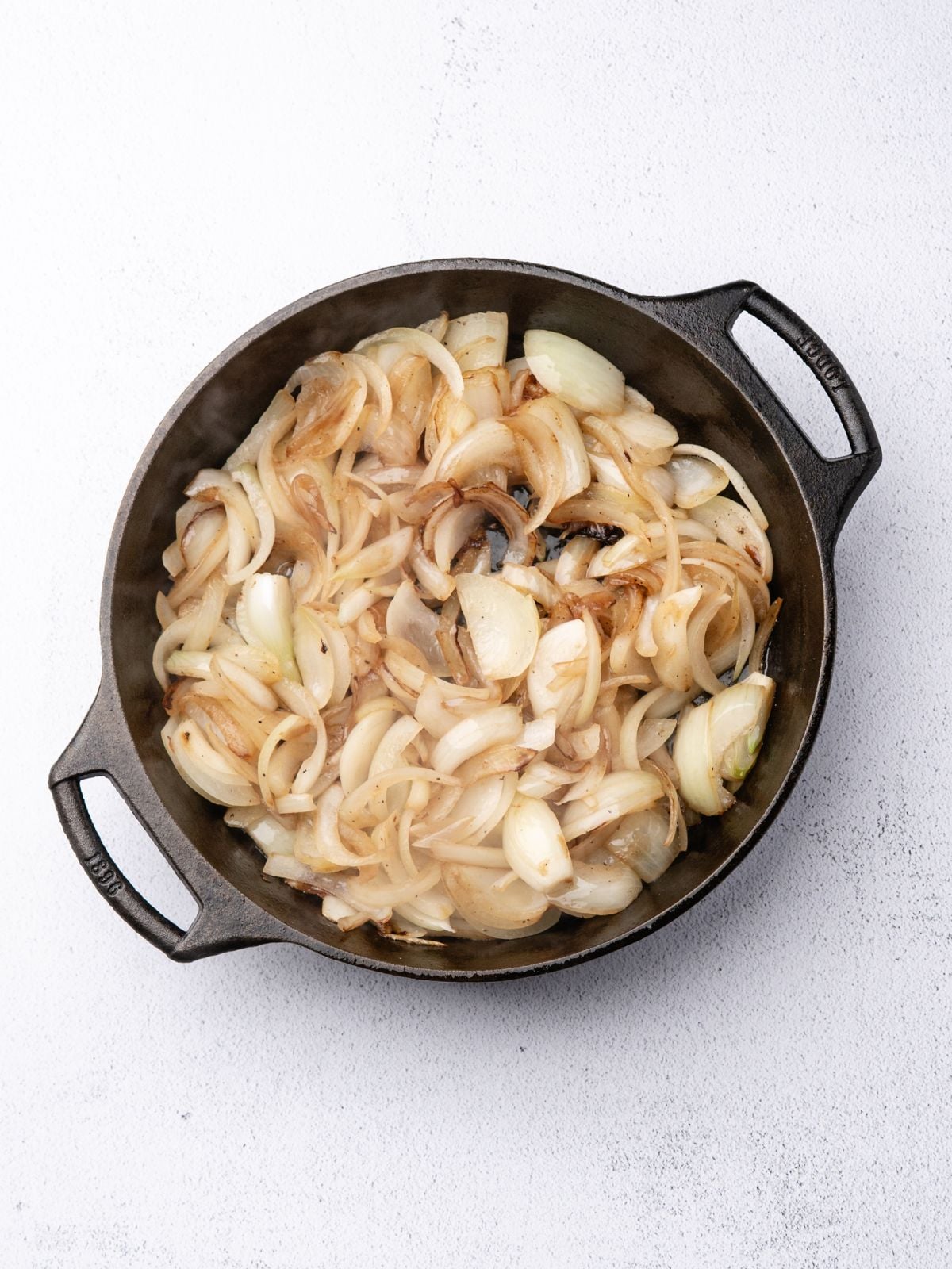 Sautéed sliced onions in a cast-iron skillet.