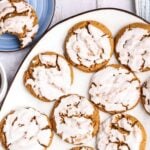 Glazed round cookies on a white platter, with a partially eaten cookie on a blue plate nearby.
